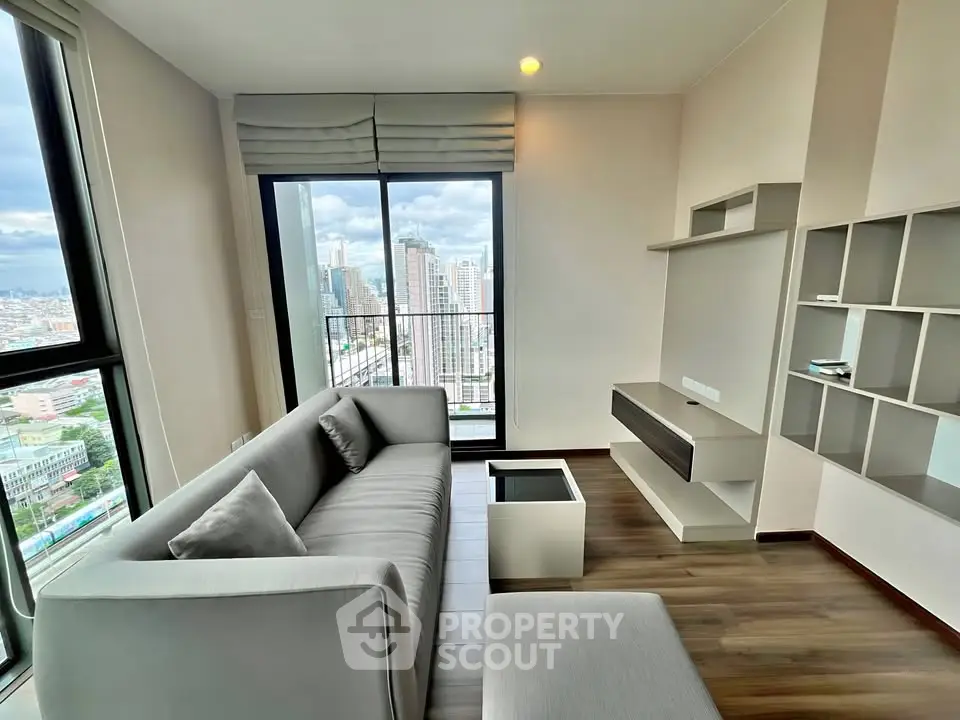 Modern living room with city view, featuring sleek furniture and large windows for natural light.