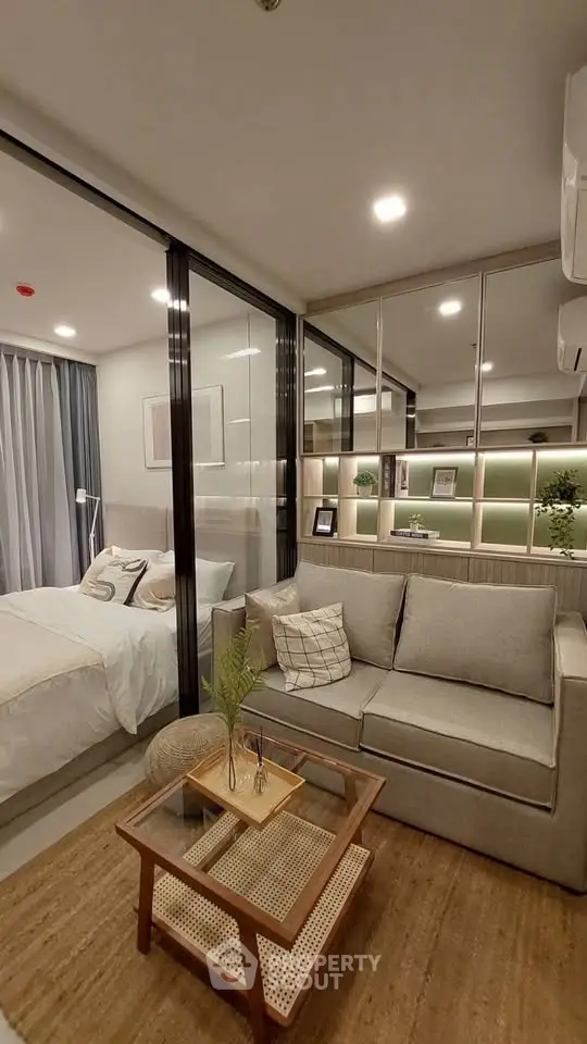 Modern studio apartment with glass partition, cozy living area, and stylish bedroom.