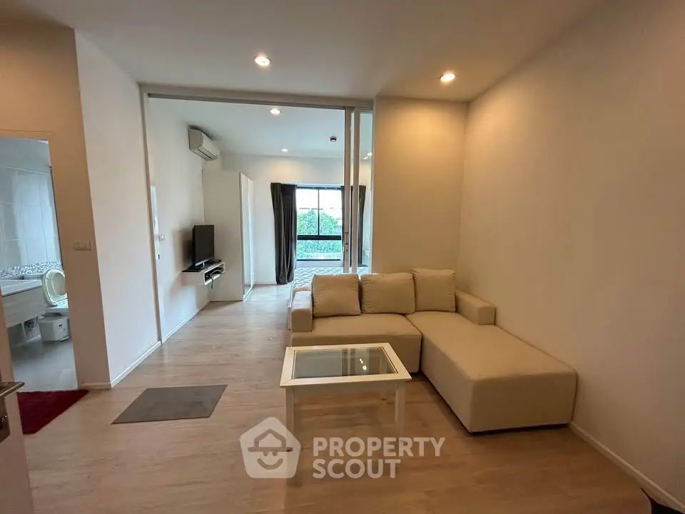 Modern living room with cozy beige sofa and glass coffee table, featuring open layout and natural light.