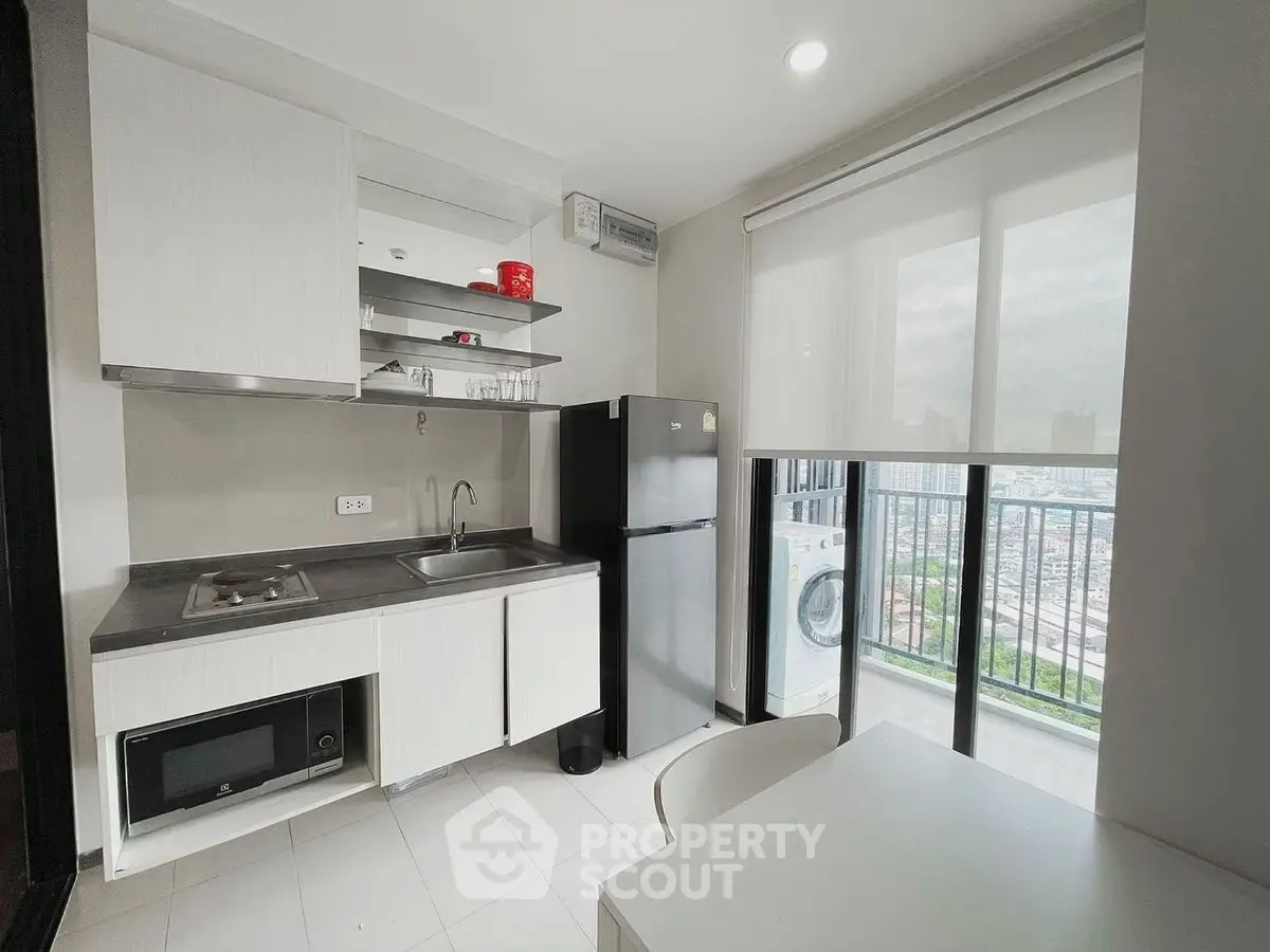 Modern kitchen with balcony view, featuring sleek appliances and ample natural light.