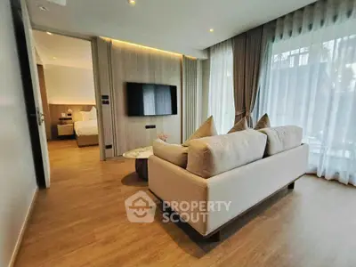 Modern living room with cozy sofa and wall-mounted TV, leading to a stylish bedroom.