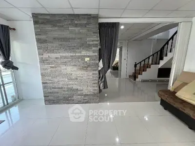 Spacious modern living room with stone accent wall and elegant staircase