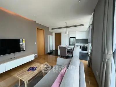 Modern open-plan living room with kitchen, featuring sleek furniture and natural light.