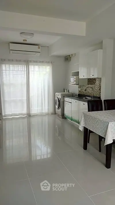 Modern kitchen with washing machine and dining area in bright apartment