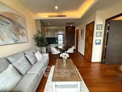 Modern living room with stylish decor and open kitchen layout, featuring wooden flooring and elegant furniture.