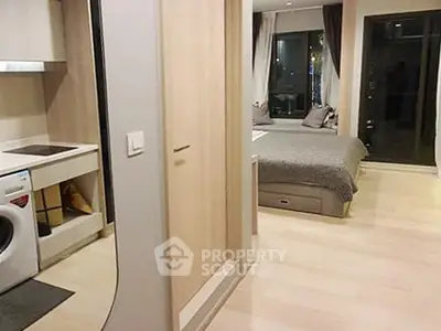 Modern studio apartment with cozy bedroom and compact kitchen featuring washing machine.