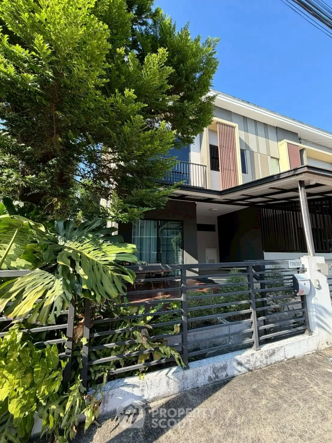 Modern two-story house with lush greenery and sleek fence design