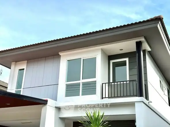 Modern two-story house with sleek design and large windows.