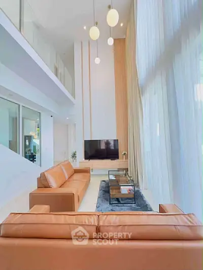 Luxurious double-height living room with modern decor and large windows.