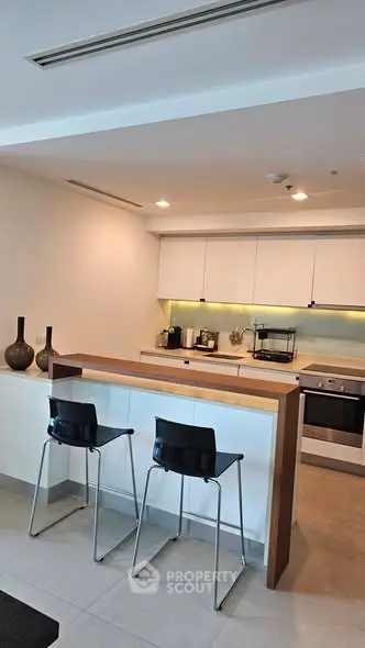 Modern kitchen with sleek design, featuring a breakfast bar and contemporary appliances.