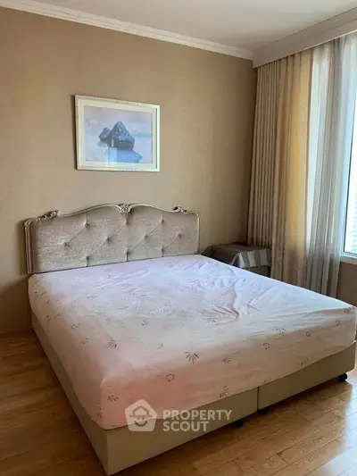 Spacious bedroom with elegant decor and large window offering natural light.