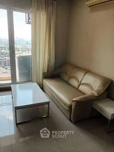 Cozy living room with leather sofa and balcony view in modern apartment.