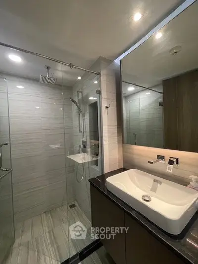 Modern bathroom with glass shower and sleek vanity in luxury apartment.