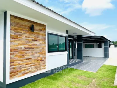 Modern single-story house with stylish stone facade and lush green lawn, perfect for contemporary living.