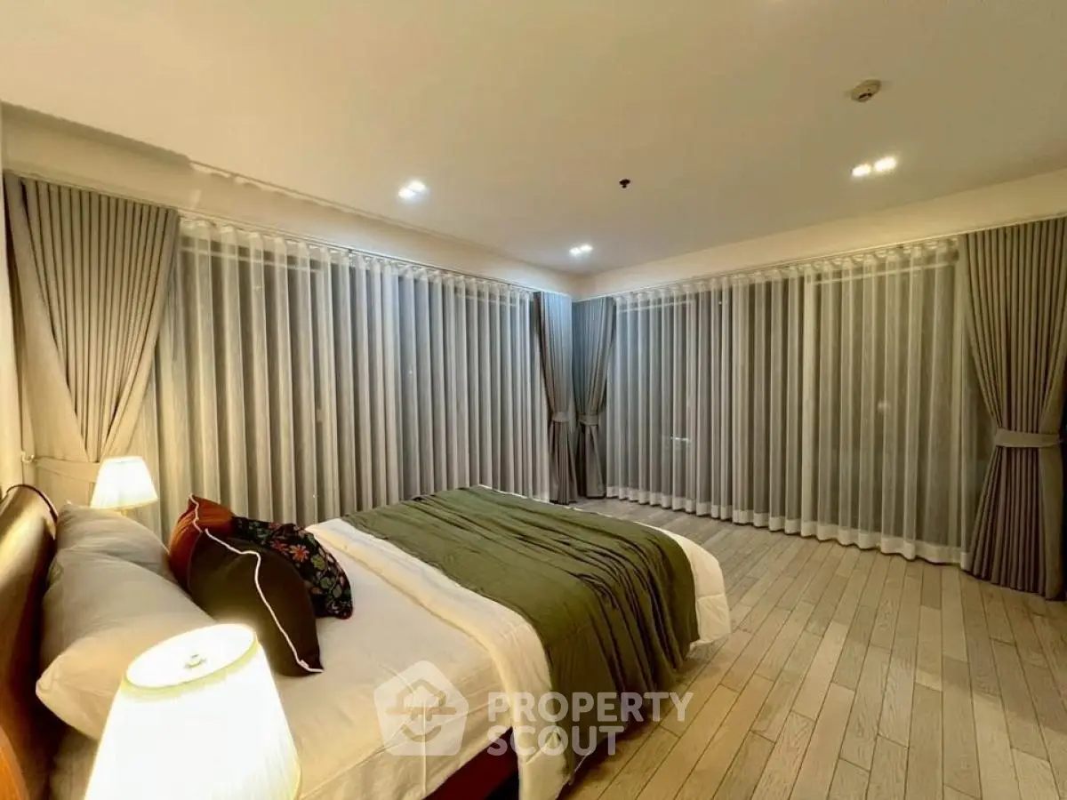 Spacious bedroom with elegant curtains and cozy lighting for a serene ambiance.