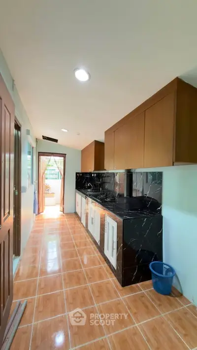 Spacious kitchen with modern black countertops and ample storage, featuring a bright and airy atmosphere.