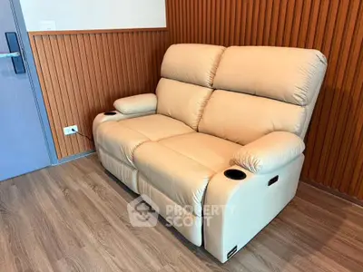 Modern living room with stylish beige recliner sofa and wooden panel wall.