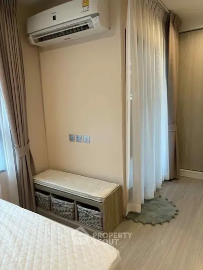 Cozy bedroom with air conditioning and elegant curtains, featuring a stylish storage bench and soft lighting.