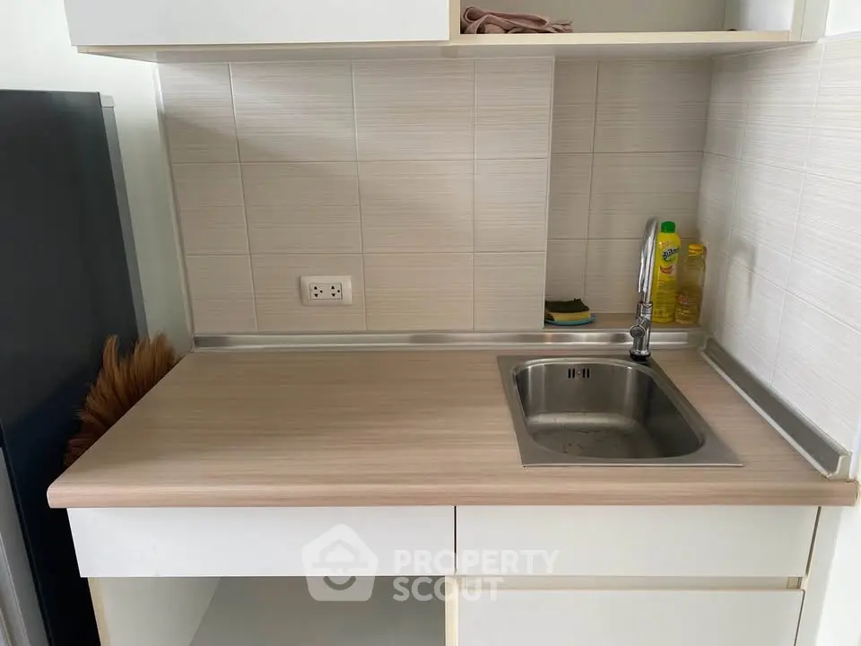 Compact kitchen with sleek countertop and stainless steel sink in modern apartment.