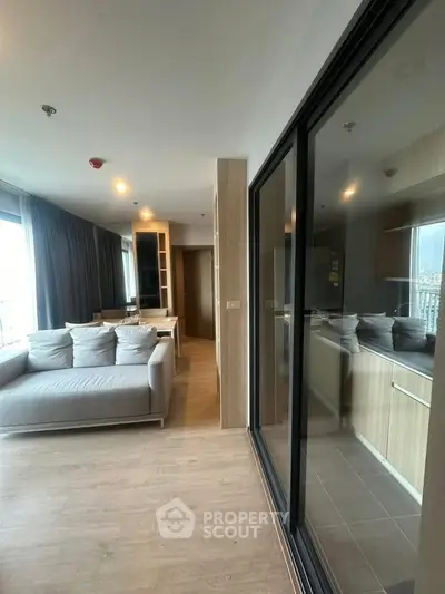 Modern living room with large windows and sleek furniture in a high-rise apartment.