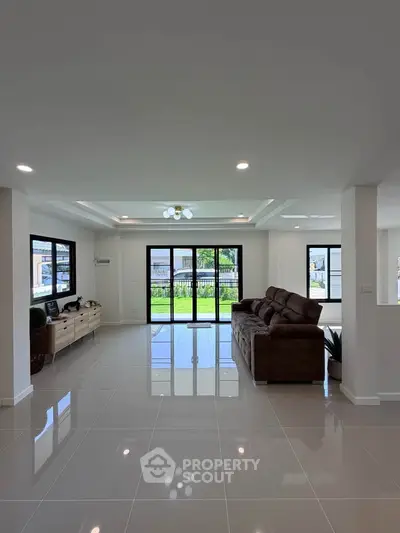 Spacious modern living room with large windows and elegant tile flooring, perfect for family gatherings.