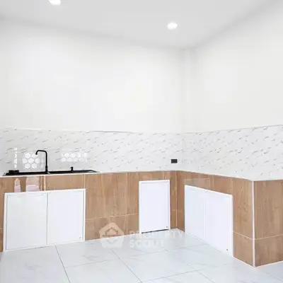 Modern kitchen with sleek design and minimalist cabinetry, featuring a stylish backsplash and ample counter space.