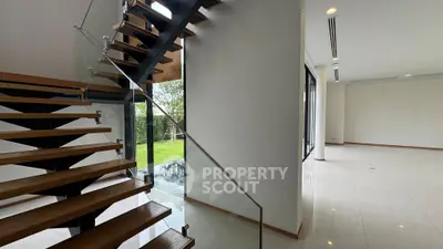Modern open-concept living space with sleek staircase and garden view.