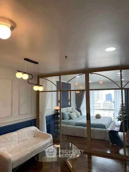 Luxurious living room with elegant decor and a view into a stylish bedroom, featuring modern lighting and plush furnishings.