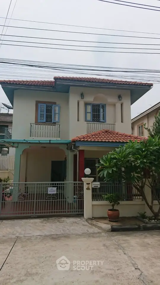 Charming two-story house with tiled roof and gated entrance in a suburban neighborhood.