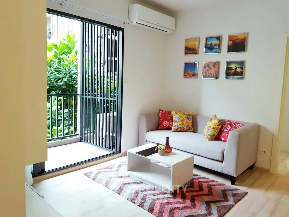 Charming living room with vibrant decor and garden view, featuring cozy sofa and modern air conditioning.