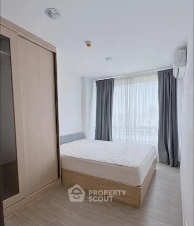 Modern bedroom with large window and wooden wardrobe in a bright apartment.