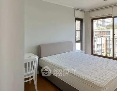 Bright and airy bedroom with large windows and modern furnishings in a city apartment.