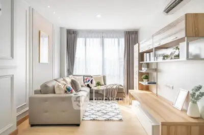 Modern living room with stylish decor and natural light, featuring a cozy sofa and elegant shelving.