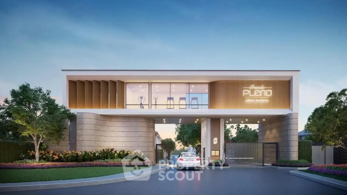 Elegant gated entrance of modern residential complex with sleek design and lush landscaping.