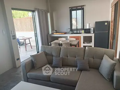 Modern living room with open layout and outdoor patio access, featuring a cozy sofa and compact kitchen area.