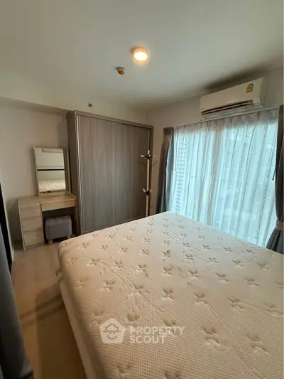Cozy bedroom with large window and modern furnishings in a stylish apartment.