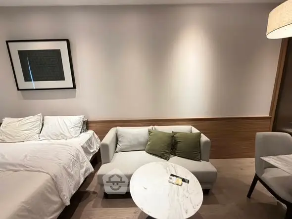 Modern studio apartment with cozy bed and stylish seating area, perfect for urban living.