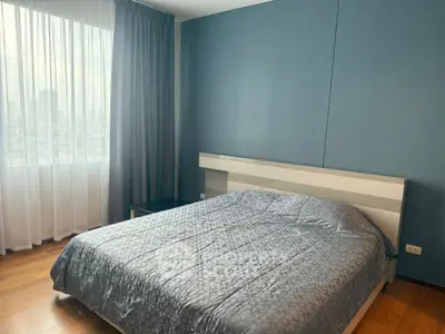 Modern bedroom with city view and elegant decor, featuring a cozy bed and large window.