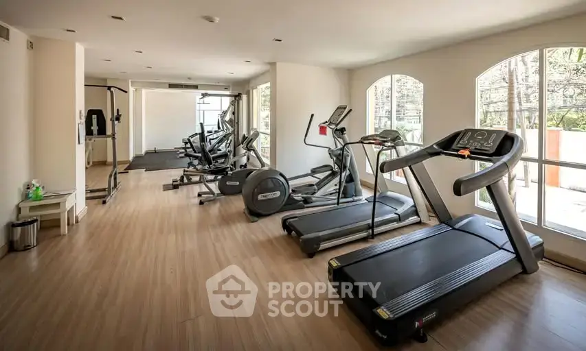Spacious gym with modern equipment and large windows in a residential building.