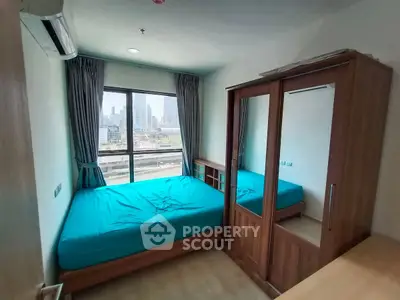 Cozy bedroom with city view, featuring a double bed and wooden wardrobe, ideal for urban living.