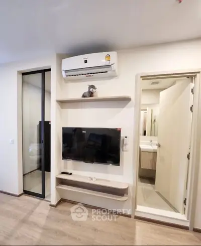 Modern living room with air conditioning and TV, adjacent to a bathroom, showcasing sleek design and functionality.