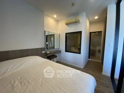Modern bedroom with sleek design, featuring a large bed, built-in desk, and air conditioning unit.
