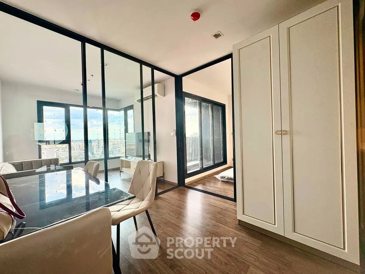 Modern apartment with glass partitions and city view, featuring elegant dining area and spacious layout.