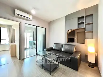 Modern living room with sleek black sofa, glass coffee table, and built-in shelving in a stylish apartment.
