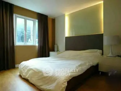 Cozy bedroom with modern lighting and large window for natural light.