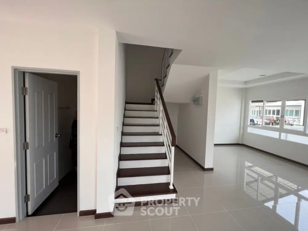 Spacious modern interior with sleek staircase and large windows, perfect for contemporary living.