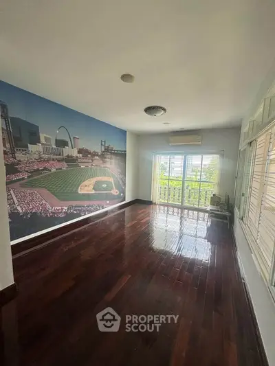 Spacious living room with hardwood floors and a large sports-themed mural, perfect for entertainment.