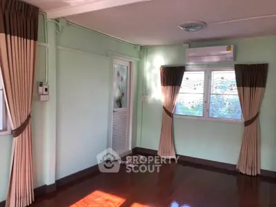 Charming room with polished wooden floors, pastel green walls, and elegant curtains, featuring air conditioning and natural light.