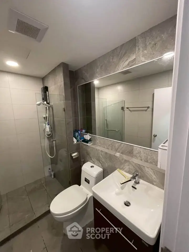 Modern bathroom with sleek fixtures and glass shower enclosure in contemporary home.