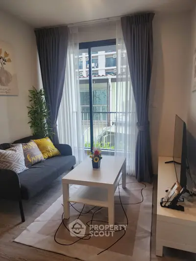 Cozy living room with modern decor, large window, and stylish furniture in a bright apartment.
